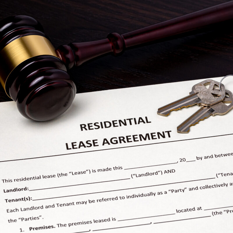 A gavel and set of keys laid on top of a lease agreement mock up